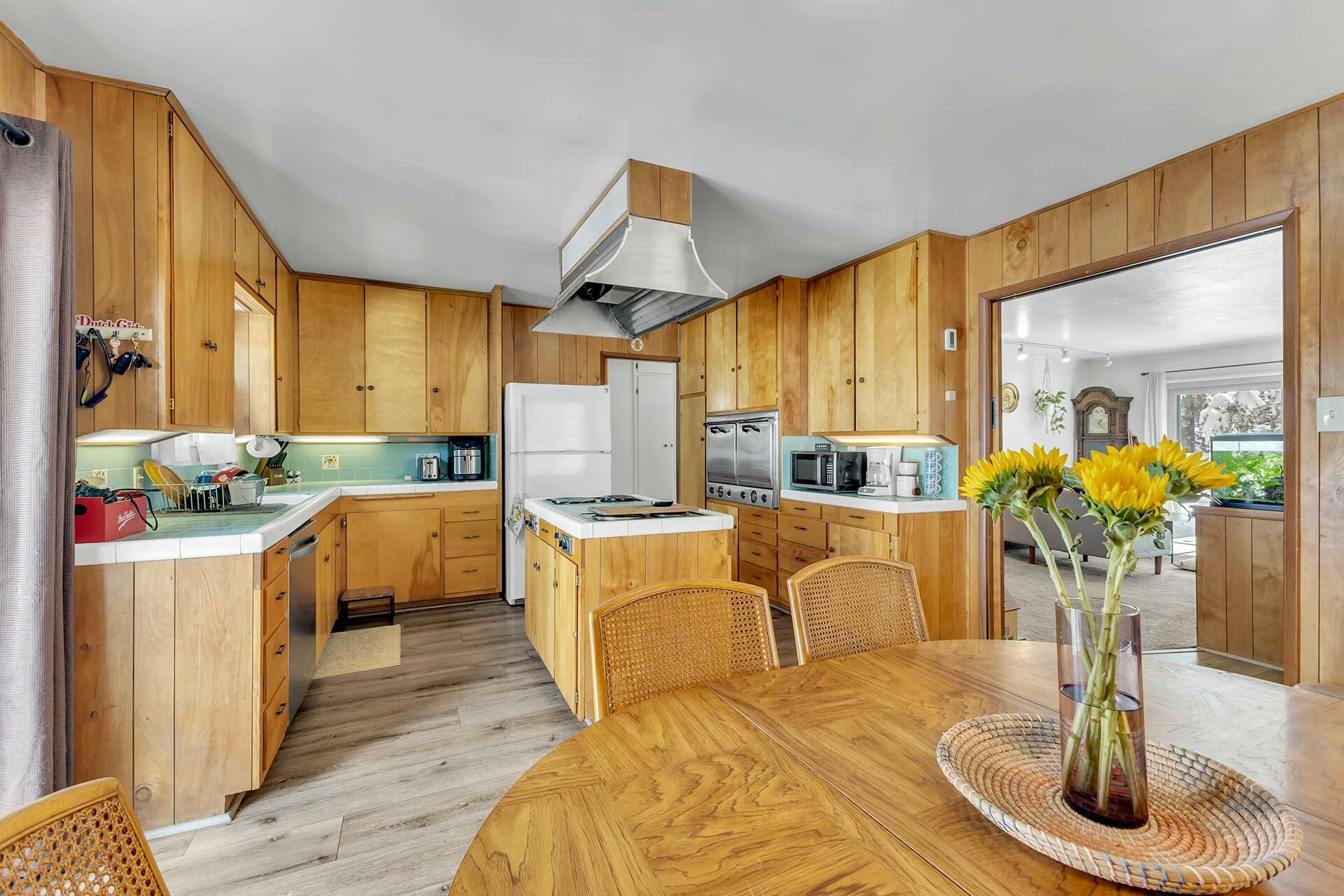 52660 Sylvan Way Idyllwild, CA 92549 - Photo 10 of 25 a kitchen with stainless steel appliances kitchen island granite countertop a refrigerator a sink dishwasher a dining table and chairs with wooden floor