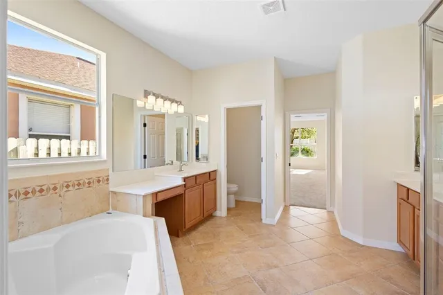 a spacious bathroom with a double vanity sink a large mirror and a bathtub