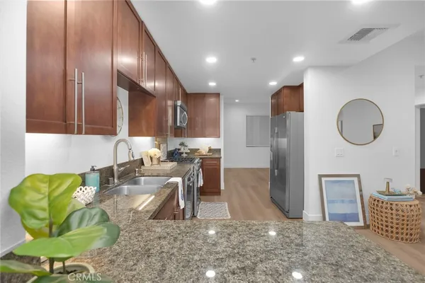 a kitchen with kitchen island granite countertop wooden cabinets and stainless steel appliances
