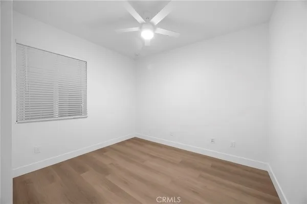 a view of a hallway with wooden floor and a kitchen