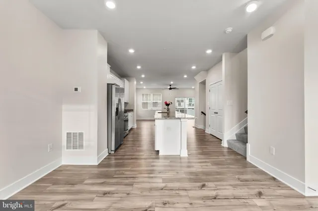a view of kitchen dining table kitchen island with stainless steel appliances wooden floor and living room view
