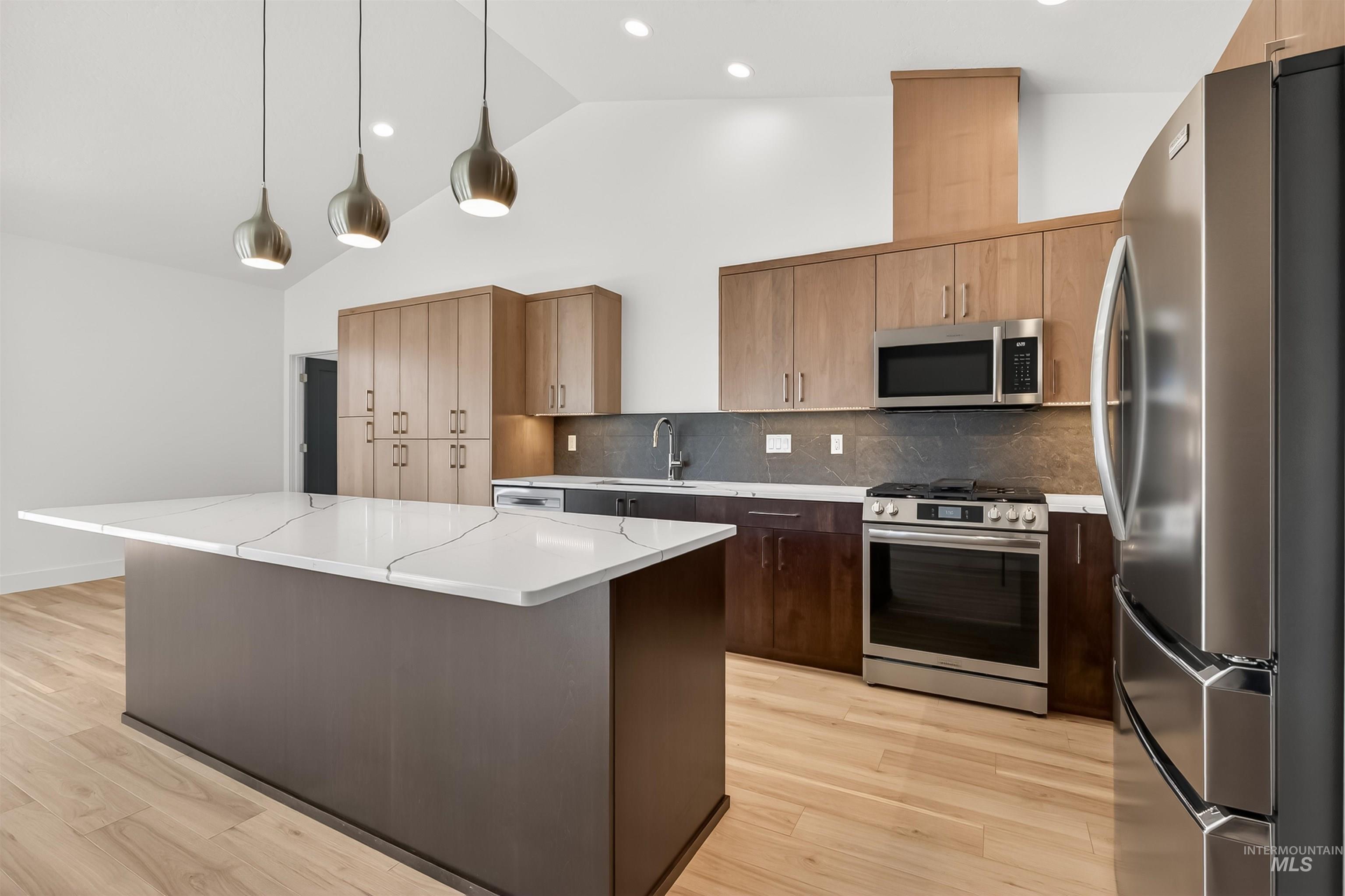 3710 22nd Street Lewiston, ID 83501 - Photo 15 of 36 Kitchen with stainless steel appliances, a kitchen island, vaulted ceiling, light wood-style floors, and hanging light fixtures