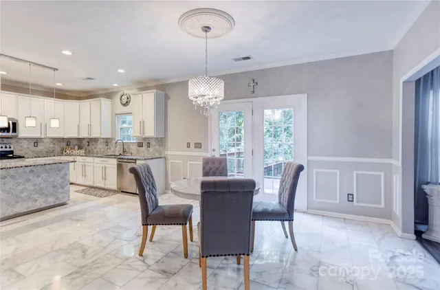 a view of a dining room and livingroom with furniture wooden floor a rug a rug a fireplace and a chandelier