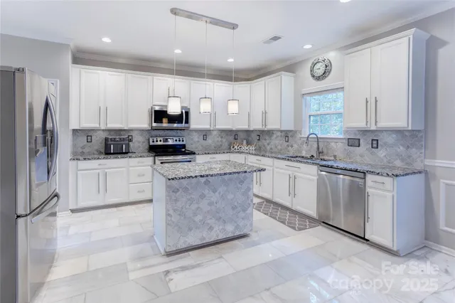 a kitchen with kitchen island granite countertop a sink a counter top space stainless steel appliances and cabinets