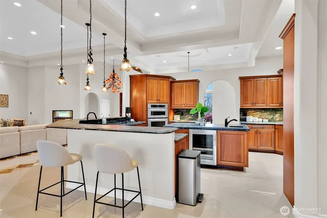 a kitchen with stainless steel appliances granite countertop a stove a sink a oven a counter space and chairs