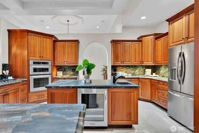 a kitchen with kitchen island granite countertop wooden cabinets stainless steel appliances a sink and a window