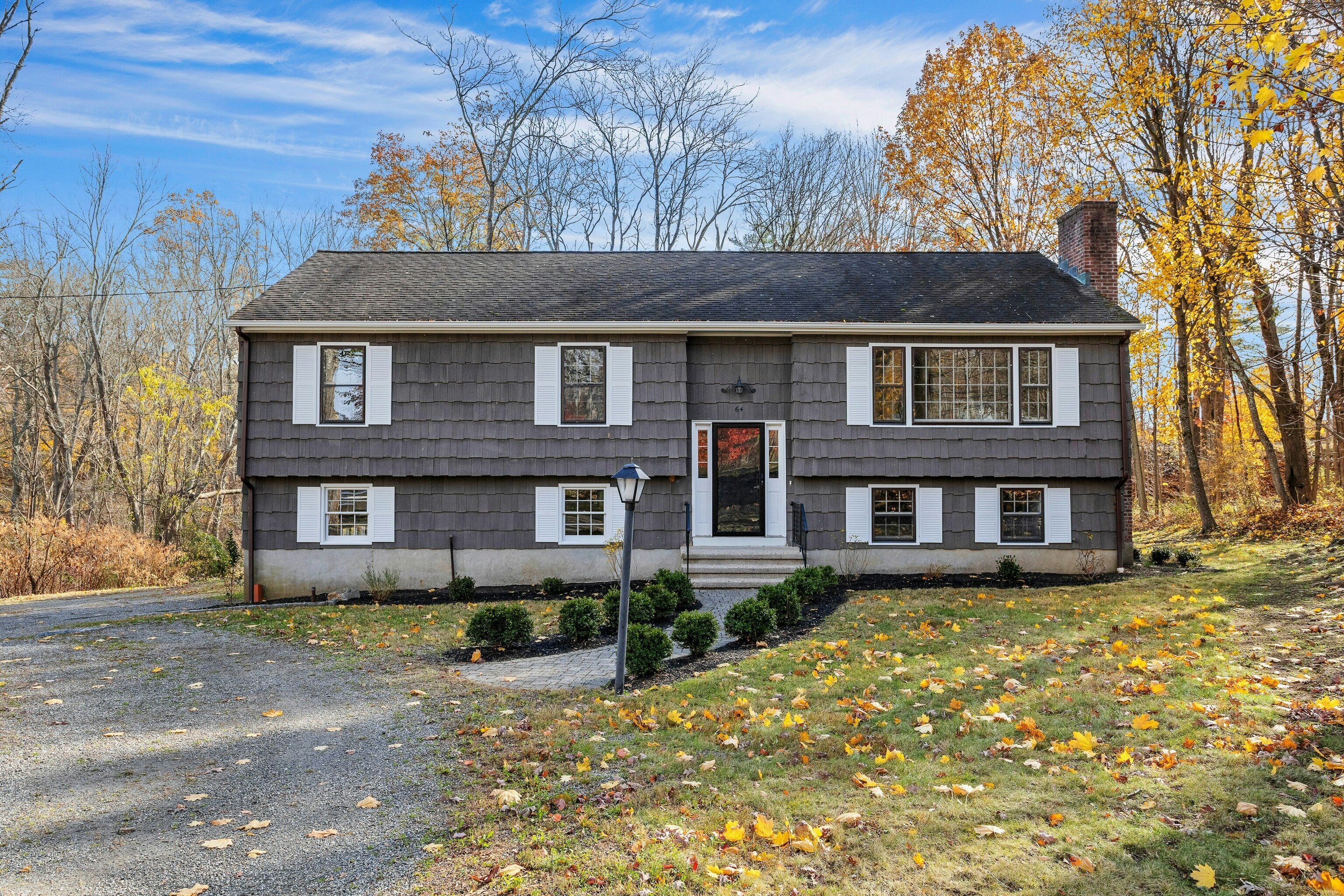 a front view of a house with a garden and trees