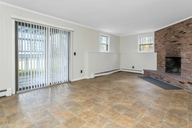 a view of an empty room with a fireplace and a window