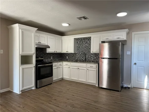 a kitchen with a refrigerator stove and wooden cabinets