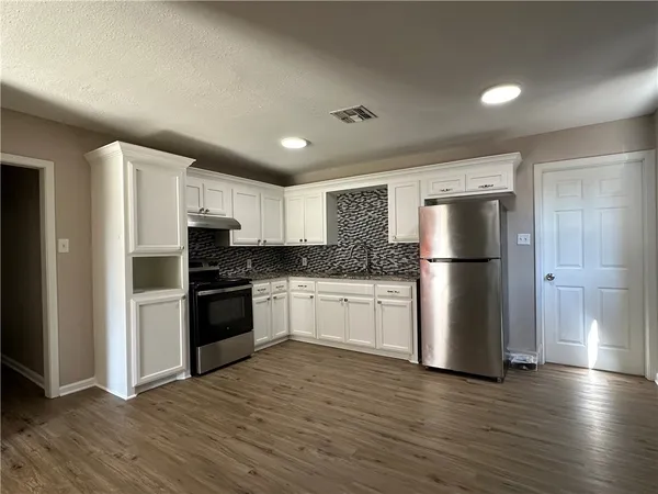 a kitchen with a refrigerator and a stove top oven