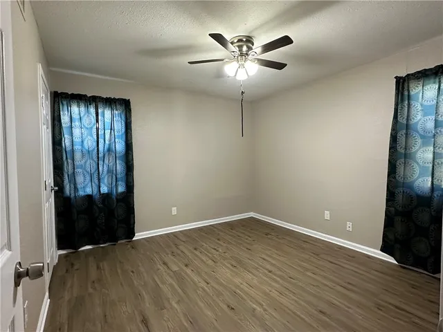 an empty room with wooden floor closet and windows