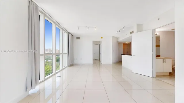 a view of a hallway with wooden floor and a refrigerator