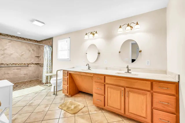 a spacious bathroom with double vanity sink a mirror and bathtub