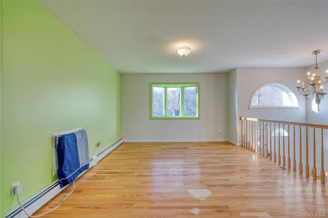 a view of an empty room with window and wooden floor