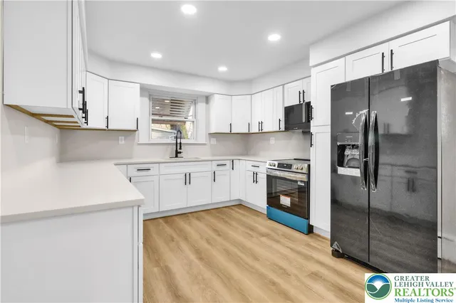 a kitchen with stainless steel appliances granite countertop a sink a stove a refrigerator and white cabinets