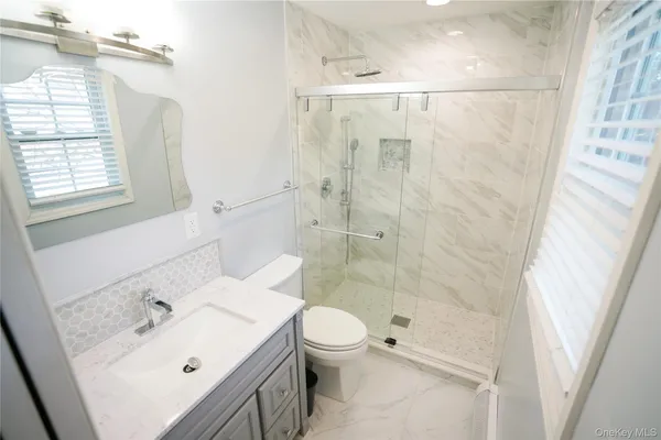 a bathroom with a granite countertop toilet sink and mirror