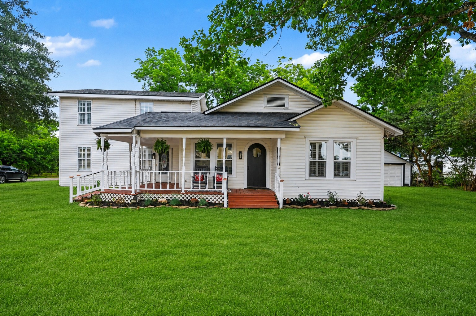 Charming white two-story house welcoming front porch.