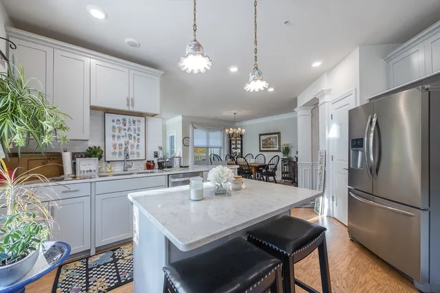 a kitchen with stainless steel appliances granite countertop a refrigerator a sink dishwasher a dining table and chairs with wooden floor