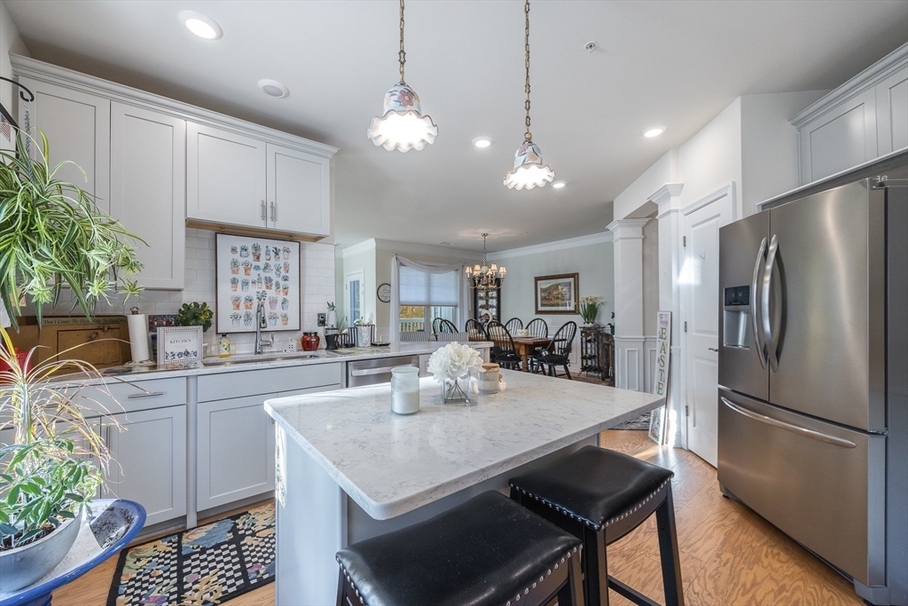 4 Francis Drive, Unit 207 Andover, MA 01810 - Photo 3 of 21 a kitchen with stainless steel appliances granite countertop a refrigerator a sink dishwasher a dining table and chairs with wooden floor