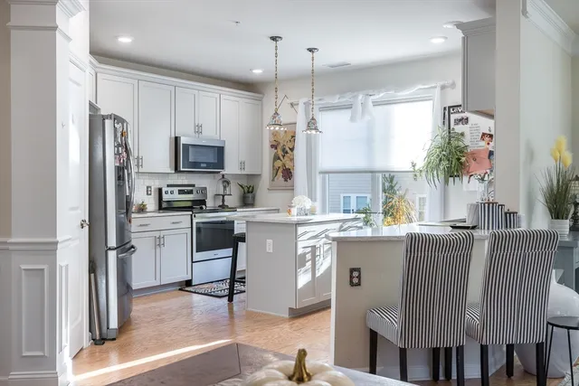 a kitchen with stainless steel appliances granite countertop a refrigerator a stove a sink dishwasher and a dining table with wooden floor