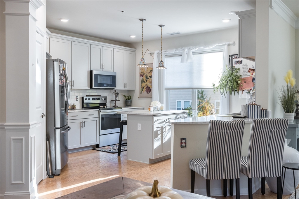 4 Francis Drive, Unit 207 Andover, MA 01810 - Photo 4 of 21 a kitchen with stainless steel appliances granite countertop a refrigerator a stove a sink dishwasher and a dining table with wooden floor