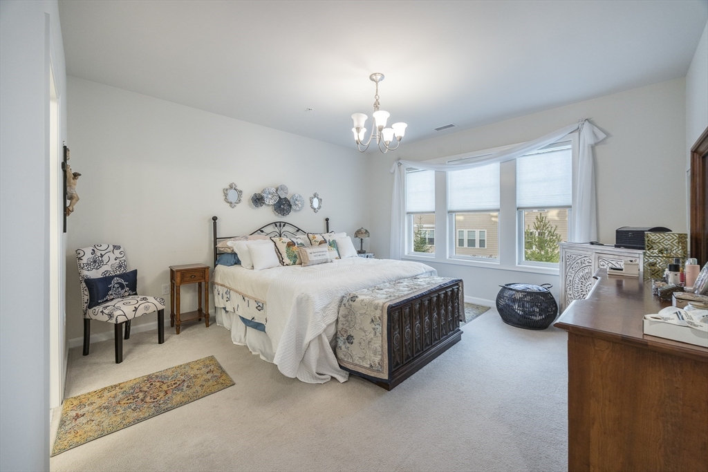 4 Francis Drive, Unit 207 Andover, MA 01810 - Photo 9 of 21 a bedroom with a bed and a chandelier