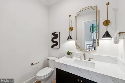 a bathroom with a granite countertop sink a toilet and mirror