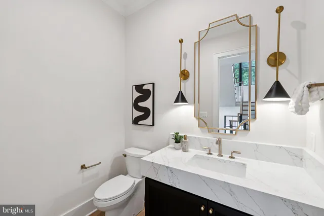 a bathroom with a granite countertop sink a toilet and mirror