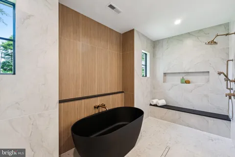 a view of a hallway with wooden floor and a bathroom