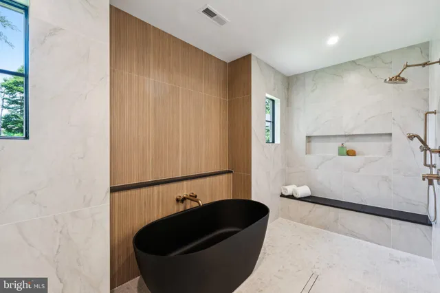 a view of a hallway with wooden floor and a bathroom