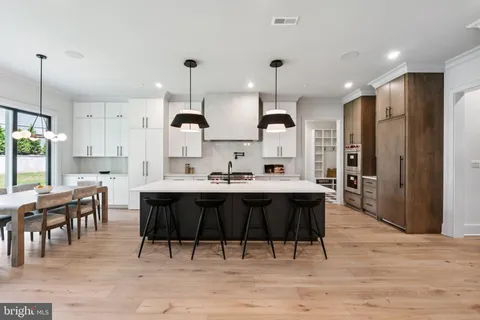 a kitchen with stainless steel appliances kitchen island granite countertop a table chairs sink and cabinets