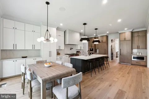 a kitchen with kitchen island a dining table chairs sink and cabinets
