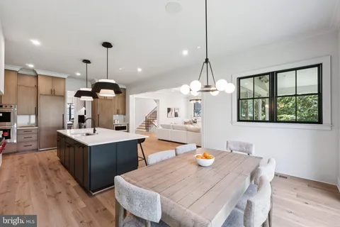 a kitchen with a stove a refrigerator a sink dishwasher with a dining table and chairs with wooden floor