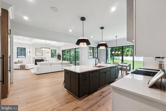 a kitchen with a stove a sink a refrigerator and a dining table with wooden floor