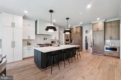 a kitchen with kitchen island a stove a sink a refrigerator and a wooden floor