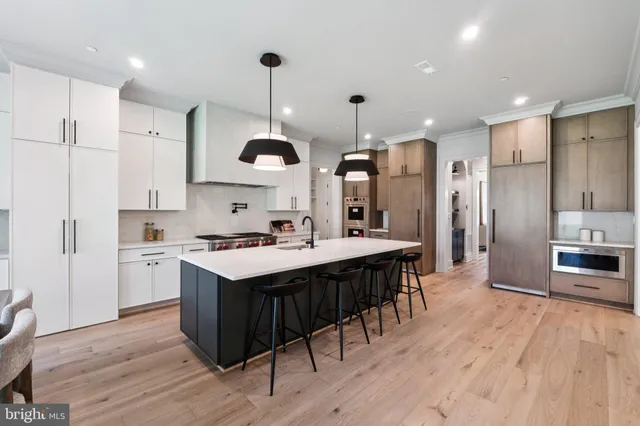 a kitchen with kitchen island a stove a sink a refrigerator and a wooden floor