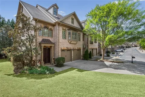 a front view of a house with a garden and tree