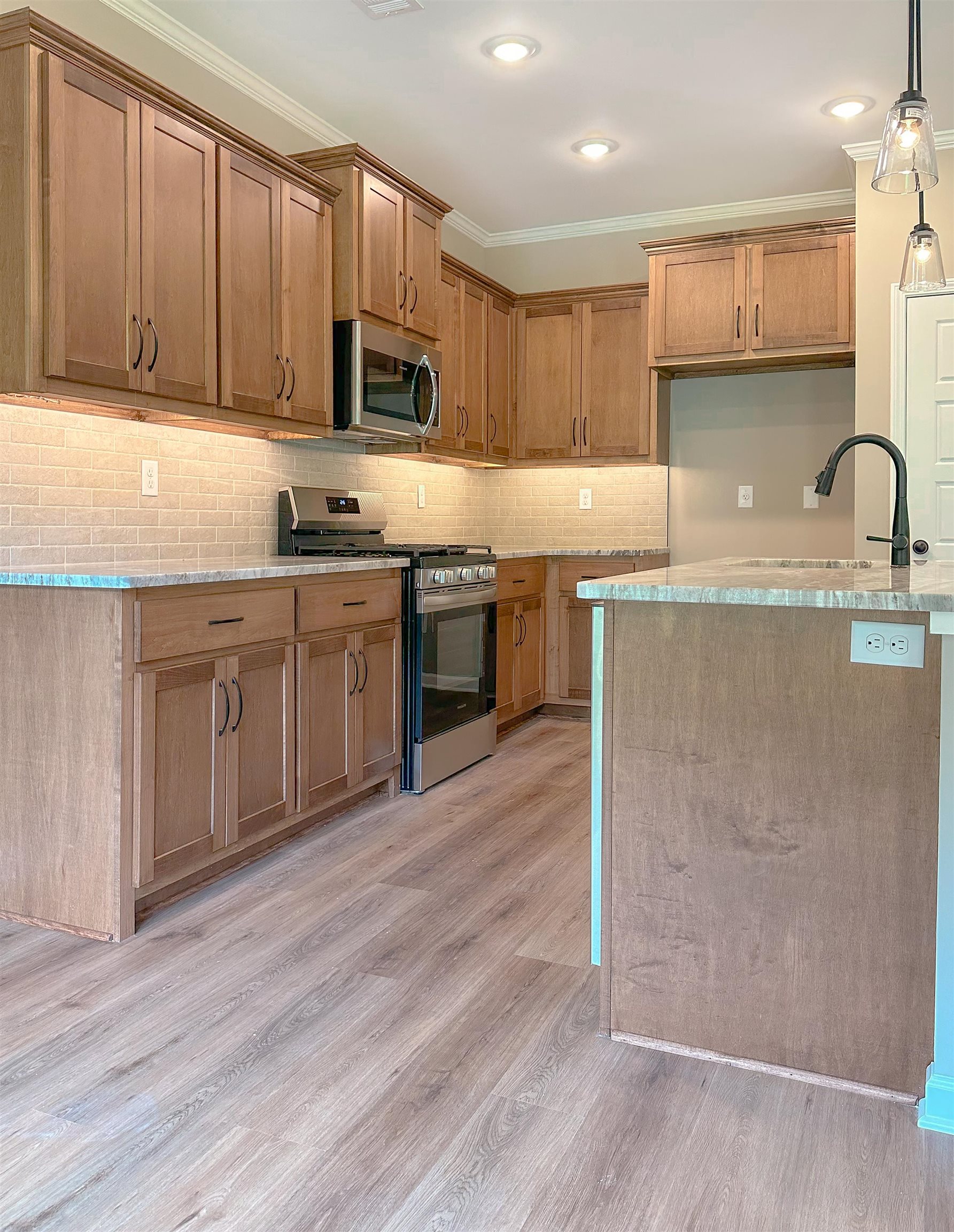 126 Stewart Road Munford, TN 38058 - Photo 11 of 23 Kitchen featuring pendant lighting, stainless steel appliances, ornamental molding, and light wood-type flooring