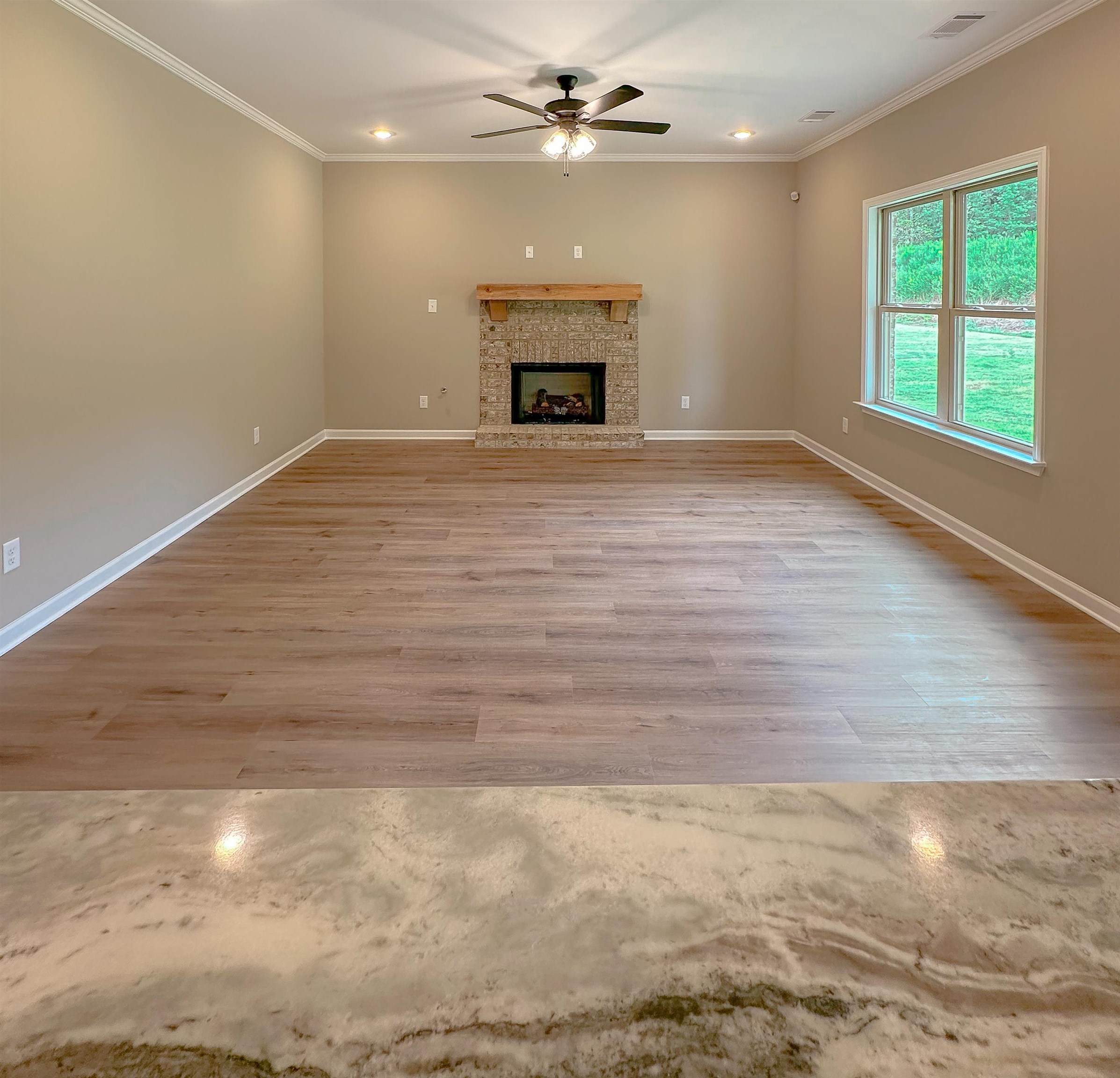 126 Stewart Road Munford, TN 38058 - Photo 6 of 23 Unfurnished living room with crown molding, ceiling fan, a brick fireplace, and light hardwood / wood-style floors