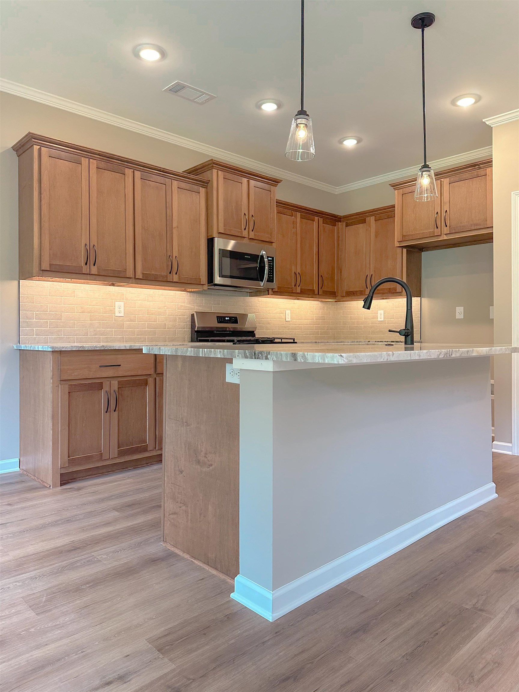 126 Stewart Road Munford, TN 38058 - Photo 8 of 23 Kitchen with light wood-type flooring, stainless steel appliances, an island with sink, light stone countertops, and hanging light fixtures