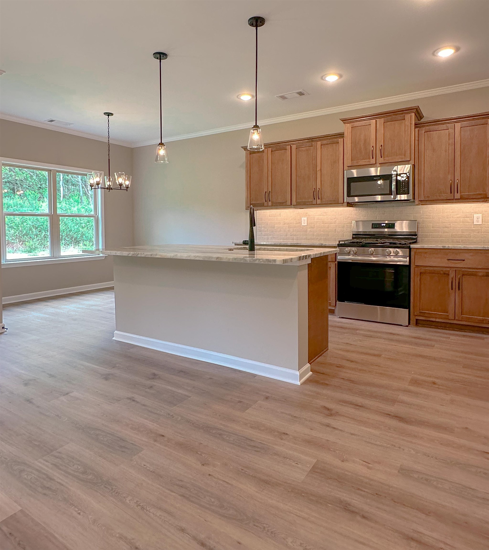 126 Stewart Road Munford, TN 38058 - Photo 9 of 23 Kitchen featuring appliances with stainless steel finishes, light hardwood / wood-style floors, a center island with sink, and pendant lighting