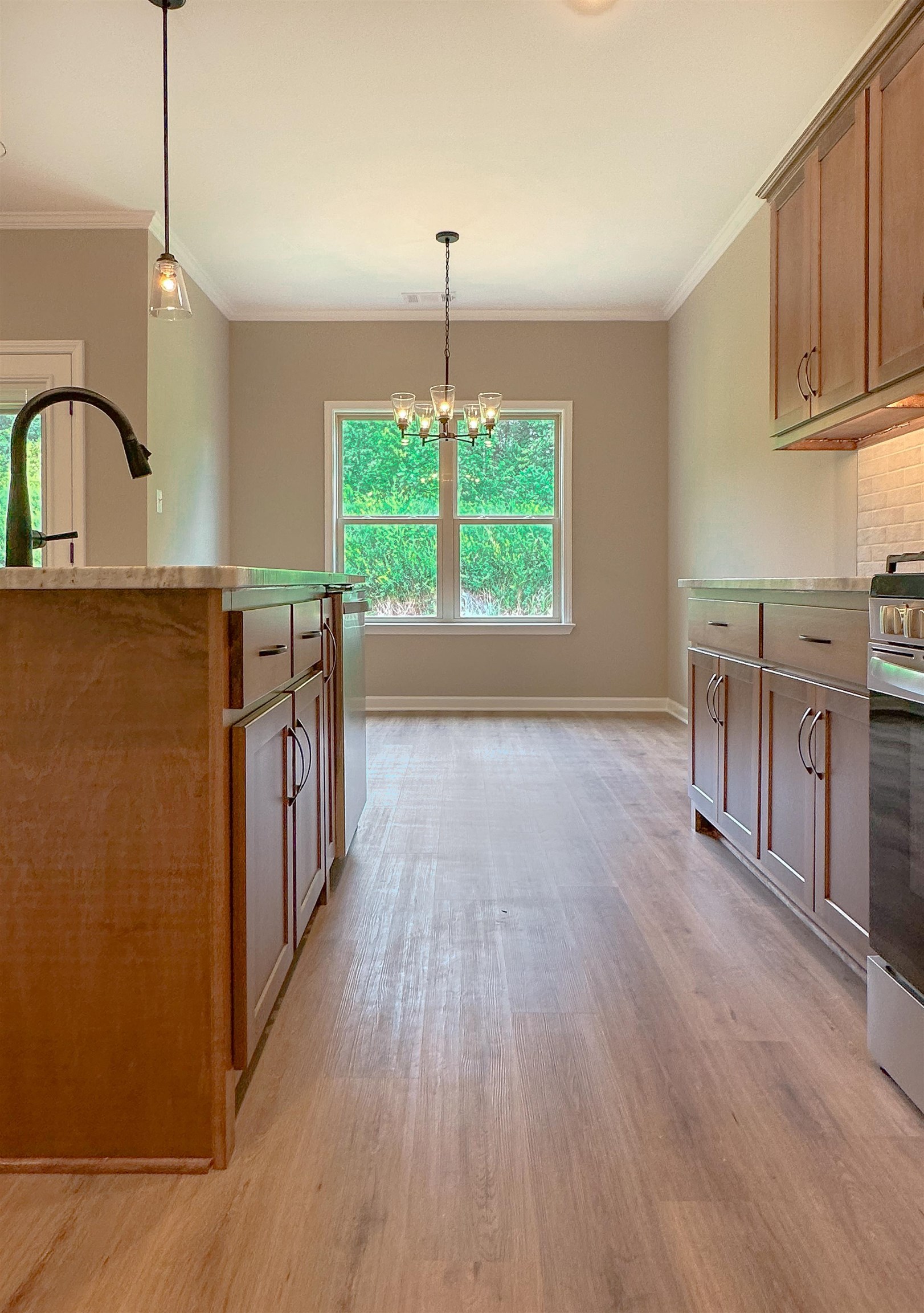 126 Stewart Road Munford, TN 38058 - Photo 10 of 23 Kitchen with crown molding, stainless steel range oven, light hardwood / wood-style floors, a notable chandelier, and pendant lighting