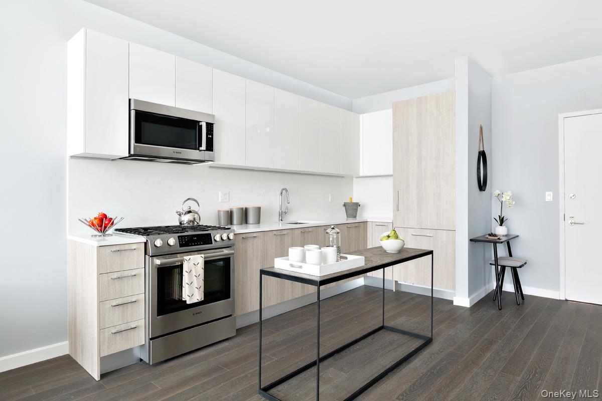 131-03 40 Road, Unit 11J Queens, NY 11354 - Photo 4 of 24 a kitchen with stainless steel appliances granite countertop a stove a sink and a microwave