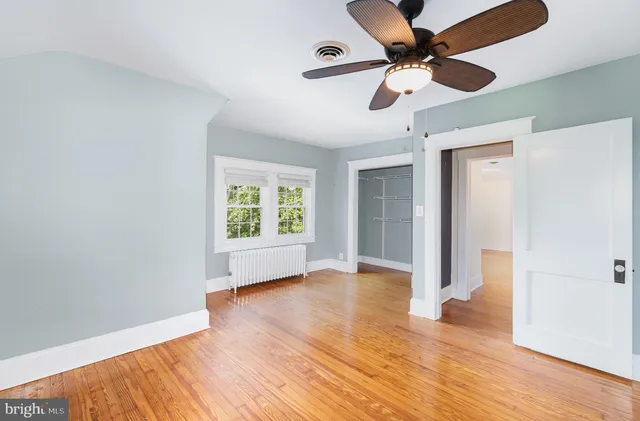 a view of an empty room with window and wooden floor