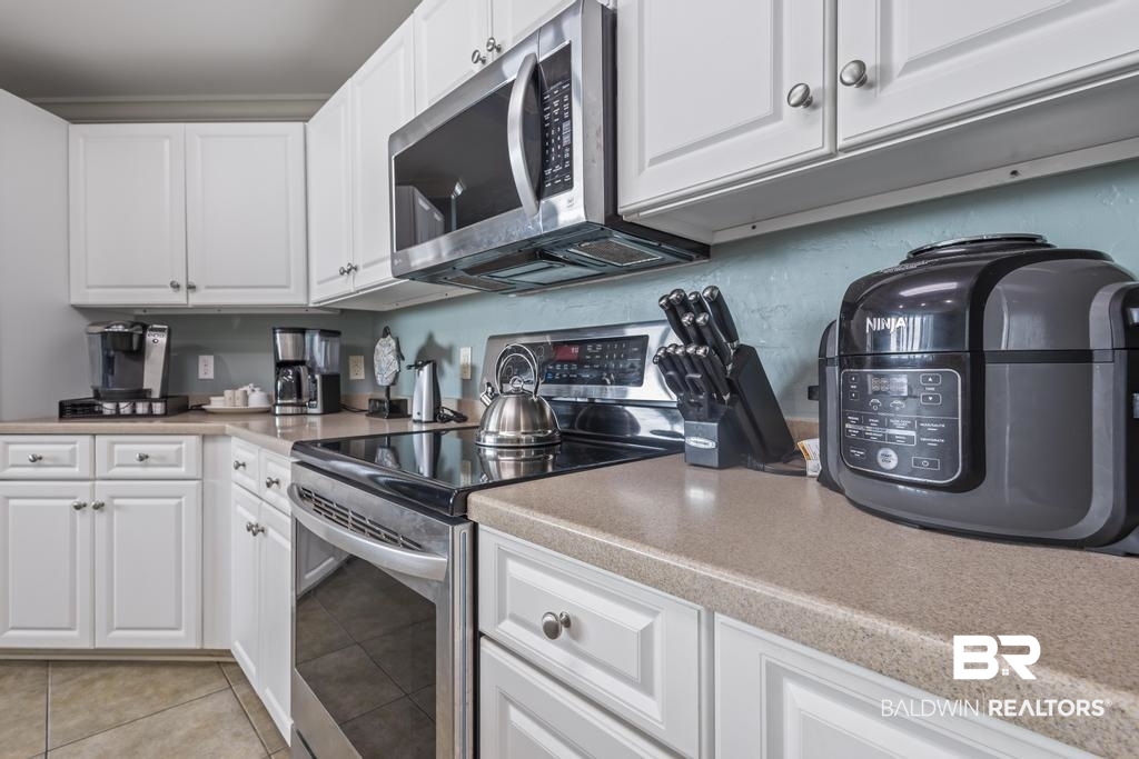 27582 Canal Road, Unit 2408 Orange Beach, AL 36561 - Photo 3 of 47 Kitchen with stainless steel appliances, white cabinetry, and light tile patterned floors