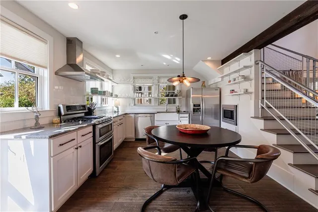a kitchen with stainless steel appliances kitchen island a table and chairs in it