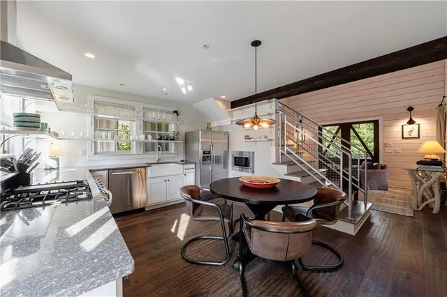 a kitchen with stainless steel appliances kitchen island granite countertop a table chairs and a wooden floor