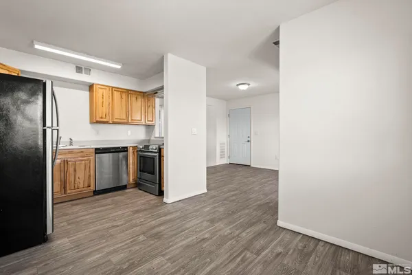 a kitchen with stainless steel appliances a refrigerator and a hard wood floor