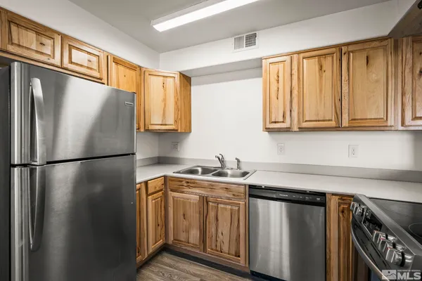 a kitchen with stainless steel appliances granite countertop a refrigerator a sink a stove and white cabinets