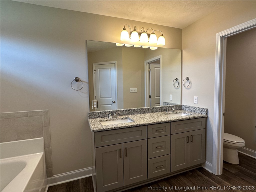 2526 Sand Hill Road Fayetteville, NC 28306 - Photo 31 of 40 a bathroom with a granite countertop sink a toilet and a large mirror